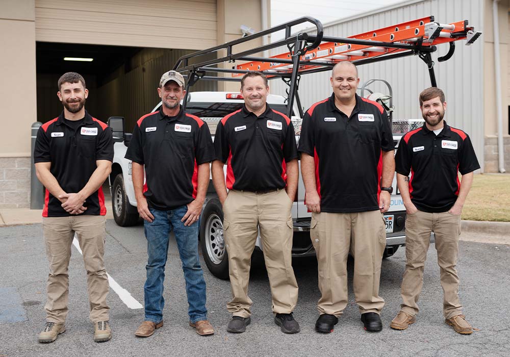 A group of skilled professionals collaborating in a repair shop, surrounded by tools and equipment, demonstrating teamwork.