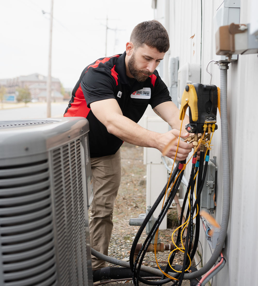 A technician is engaged in servicing an air conditioner, carefully inspecting the unit and making necessary adjustments.